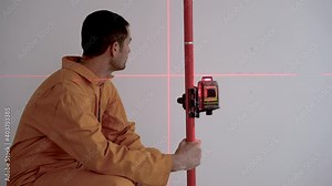 Professional worker using laser level in construction at construction site. Builder adjusting the laser level