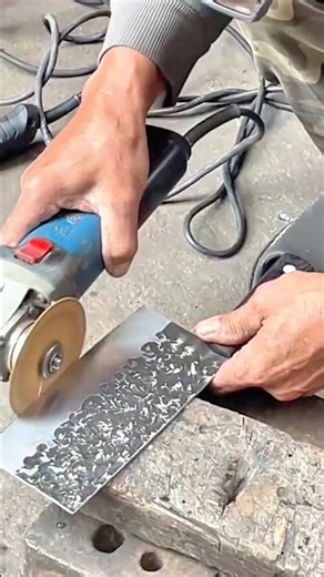 Applying dark gray adhesive to install floor tiles using manual metal trowel