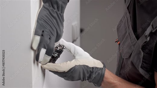 Electrician installing electrical wall switch and connecting wires inside wall using screwdriver. Concept of professional electrical work, home renovation and safe installation.