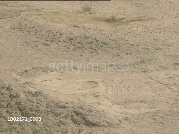 Pool of thick and gloopy bubbling mud popping and sloshing