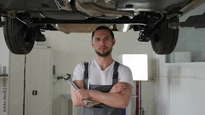 Portrait professional mechanic, repair station, auto repairman standing with arms crossed, spanner in hands, car service, against Car on hydraulic lift, Men mechanician, with tool,