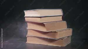 A stack of old dusty books falls on the table, a stack of old books, slow motion