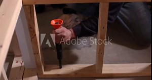Construction worker using a powder actuated tool drives a fastener into a concrete floor with precision and skill. Selective focus Stock Video
