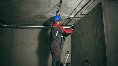 clip-3983972577-focused-electrician-securing-cables-conduit-on-concrete