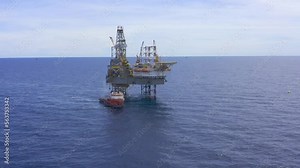 Aerial view from a drone of an offshore jack up rig, oil platform and offshore supply vessels at the offshore location during day time