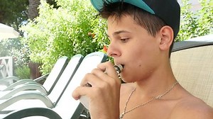 young man vaping near a pool on deck chair, slow motion 2