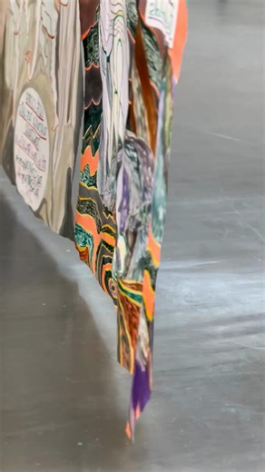 Auf der Empore zeigen wir die beeindruckende Arbeit „Ghost Calls“ der britischen Künstlerin Emma Talbot. Die ca. 13 Meter lange Seidenarbeit hängt wie eine Art Vorhang mitten im Raum und bewegt sich leicht im Wind. Kleine Magnete halten die verschiedenen Seidenstücke zusammen. „Ghost Calls“ erzählt von einer Welt nach einem Systemcrash. Die Überlebenden sind auf der Suche nach Obhut und Fürsorge. Dabei verbindet Talbot wieder die visuelle und textuelle Ebene miteinander, sodass der seidene Vorha