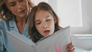 Mom kid enjoying novel spending free time at home closeup. Little girl reading