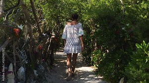 Woman tourist walks down path on small island for lunch in farè hut, New Caledonia.