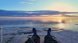 Traveler resting and relaxing at Lake Ontario Prince Edward County coast after long day. Epic sunset picturesque destination view at limestone shores and beach. Clear waters stunning view sun set. Stock Video