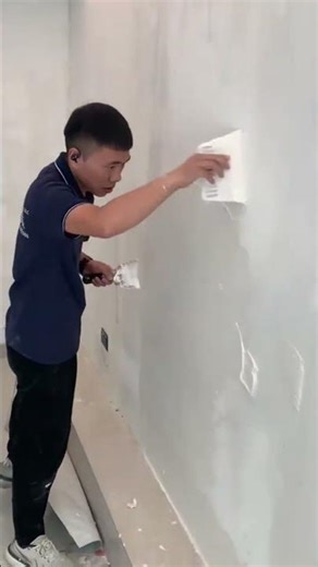 Worker using a putty knife to apply wall plaster