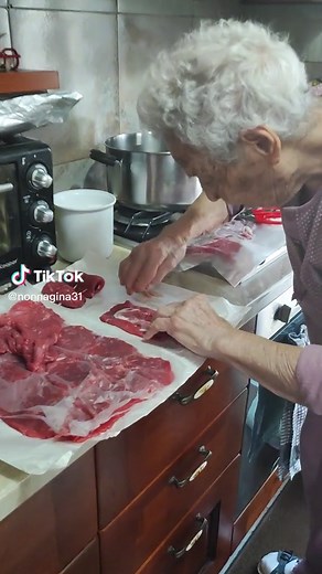 Elderly Woman Prepares Fresh Meat in Cozy Kitchen