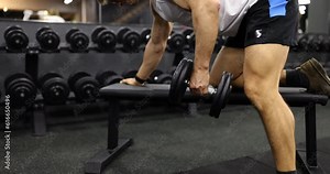 Man does lift holds heavy dumbbells in his hands and trains arm muscles. Training program in gym for man is set of strength exercises