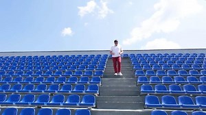 young caucasian man walking up and down the stairs in the stadium , training