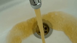 Dirty water flowing from the tap into the sink, close-up. Contamination water problem. Tap water pollution. Rust from the sink in faucet, 4k