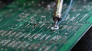 Soldering circuit board on the table, close up. soldering iron and puts it on microcircuit.