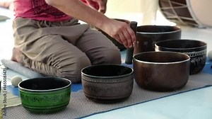 Master-class with Tibetan singing bowls, musical group plays on Tibetan singing bowls. Man operating with Tibetan singing bowls