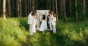 The bride goes to the groom past the applauding guests. Outdoor wedding with a priest