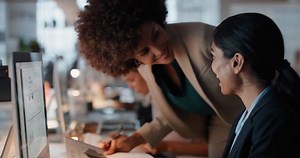 business people working late using computer team leader woman sharing information with colleague giving feedback discussing solution for project deadline in office at night