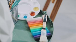 Download Over the shoulder selective focus shot of male artist using brush while adding color paint to pencil drawing on canvas for free