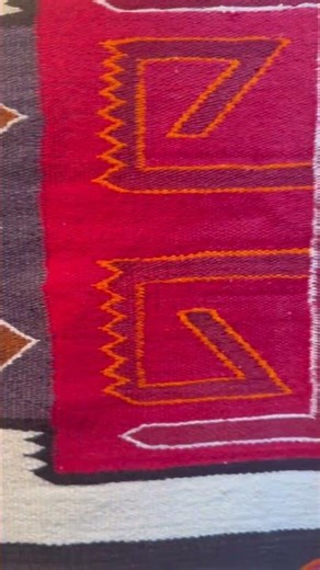 This vibrant Navajo weaving features a striking geometric design with bold, repeating motifs