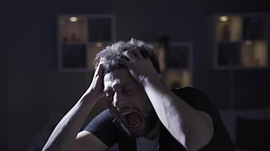 Paranoia or schizophrenia and insanity. Crazy man with mental illness driving crazy at home, screaming, having a nervous breakdown.