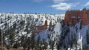 Beautiful snowy landscape of Bryce Canyon National Park in winter with its famous Tower Bridge red rock hoodoo formation and snow covered landscape, pine trees - Utah, USA.