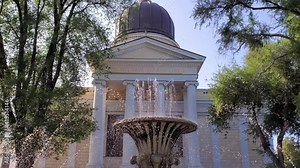 Blurry drops and jets of fountain in front of orthodox church architecture with white columns and portico. Text - God is love and power. Spaso-Preobrazhensky Cathedral in Odessa Ukraine