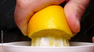 Male hand squeezing fresh lemon fruit using plastic juice squeezer. Making healthy citrus sour drink. Slow motion