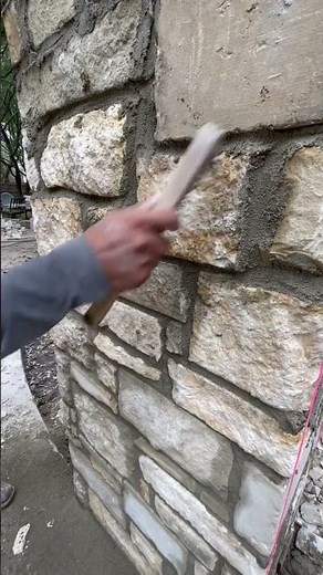 Stone wall construction (wire brushing excess mortar)