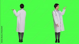 Woman medic does web advertisement against greenscreen backdrop, pointing to left and right sides in studio. Doctor with white coat advertising something for a commercial. Camera A.