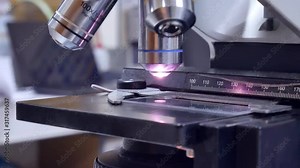 Close up hand scientist using light microscope in laboratory.
