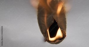 Hole burnt in a sheet of paper, completely burnt leaf. Paper burns, smoke and turns into ashes.