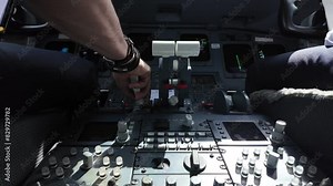 Real time scene inside a jet cockpit while flaying across turbulence area. Captain piloting the plane using speed brakes and thrust levers. Daylight. Camera between both pilots, low angle. 4K 60FPS.