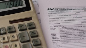 concept of paying taxes on income, push button calculator and tax returns 1040 forms, budgeting, expenses and taxes planning