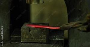 Bladesmith working with hot blade at hydraulic forge hammer