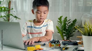 Asian kid boy learns coding and programming with laptop for Arduino robot car, Little child students typing code in computer with car toy, STEAM education AI technology course school learning Stock Video