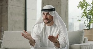 Young Arab man blogger talks speaks. Man speaks, gesticulates, explaining, talking. Arab man teacher coach blogger offers online lessons on Arabic language and culture shares his experience via webcam