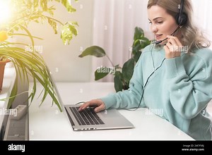 Side view head shot smiling mixed race lady freelancer wearing headset, communicating with client via video computer call. Millennial pleasant Stock Photo - Alamy