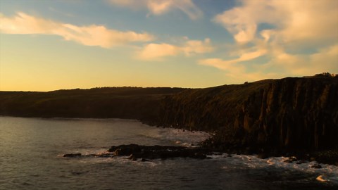 Natural waterfall on textured rock cliff in warm light