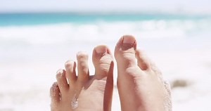 Close up of sandy feet wiggling toes on tropical beach vacation