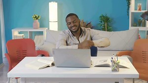 African college student dancing while studying at home. Black college student starts dancing while studying at home. Happy and cute.