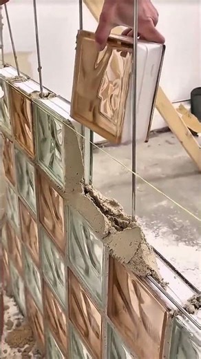 Person applying mortar to secure glass block wall