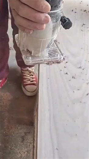 cutting a decorative edge on a wooden board using a handheld electric router tool for carpentry
