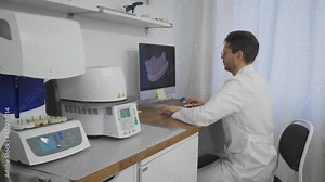 Doctor studying the digital teeth model using computer software. Doctor examines the projection of teeth model. Doctor recreates the 3D model of human teeth at the dentistry laboratory. Dental clinic