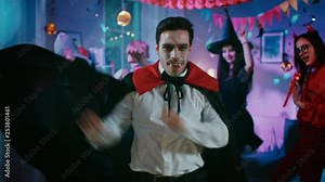 Halloween Costume Party: Count Dracula wearing His Cape Does Doing Vampire Dance, In the Background Beautiful Witch, Gorgeous She Devil and Scary Death and Zombie Dancing in the Decorated Room