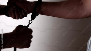 The man puts the handcuffs on his hand in one motion professionally. Theme of law enforcement, crime and justice. Man is arrest by close his hands cuffs. Hands of police officer and criminal close-up.