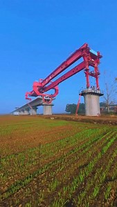 Witnessing the sheer power of this bridge girder erection machine redefines our understanding of heavy construction capabilities. 🏗️ The massive red launcher carries the prelcast concrete beam and places it seamlessly onto the waiting piers with incredible accuracy. 🌉 Utilizing such advanced heavy machinery allows for rapid infrastructure development across vast rural landscapes without disrupting the ground below. 🚄 Share your thoughts on this fascinating display of engineering efficiency in