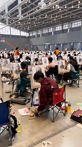 The art entrance examination in China is a grand spectacle of talent and dedication. This image captures the intensity and scale of such an event, where countless aspiring artists gather in one space to showcase their skills. The detailed portraits displayed on easels reflect the hard work and preparation that each student invests in pursuing their dreams. The organized rows of students immersed in their work demonstrate the rigor and discipline required in these high-stakes examinations. These 