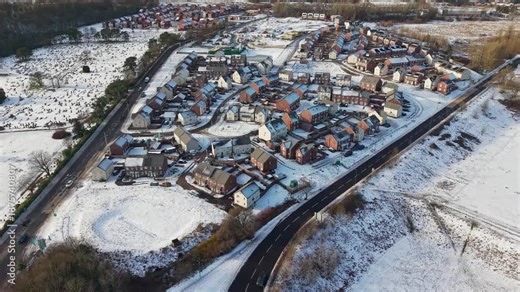 Orbiting view of modern housing estate development and cemetery in winter snow, Ebbw Vale, Wales